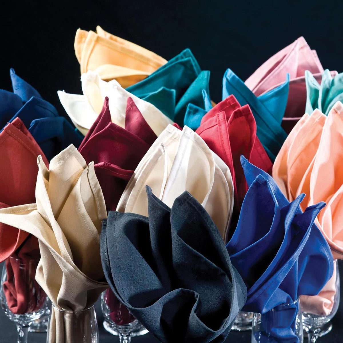 Pictured: Decorative napkins of all colors folded fancifully in a wine glass against a black background.