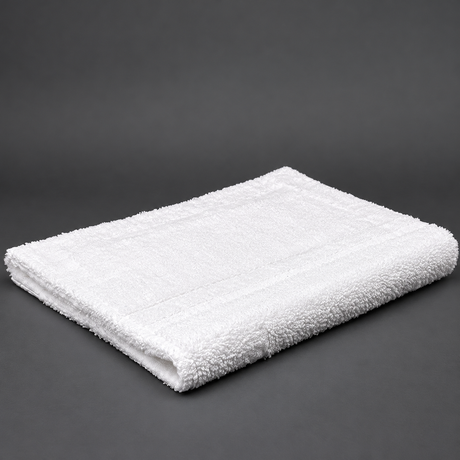 Pictured: Fluffy white rug, neatly folded, sitting against a dark grey background.