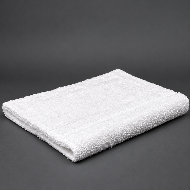Pictured: Fluffy white rug, neatly folded, sitting against a dark grey background.