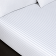 Pictured: White sheets with a striped pattern on a mattress. There are two pillows sitting on top of the sheets.