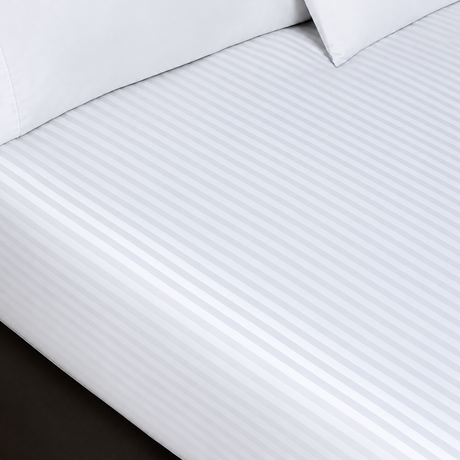 Pictured: White sheets with a striped pattern on a mattress. There are two pillows sitting on top of the sheets.