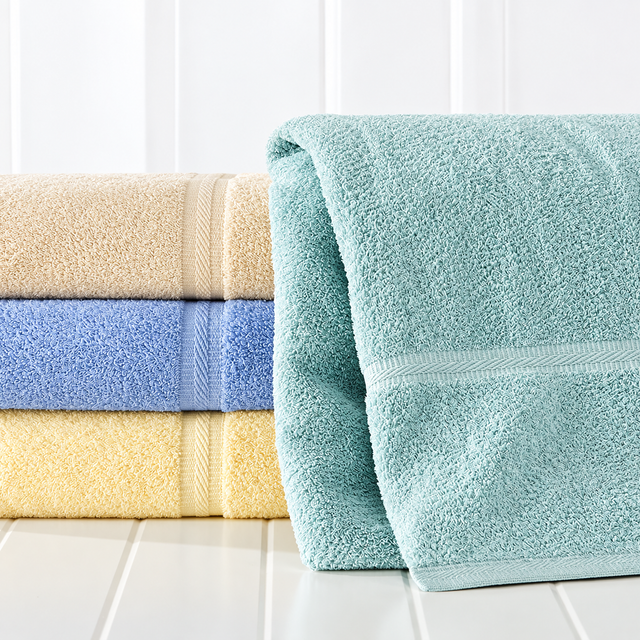Pictured: On the left are 3 solid colored towels neatly folded and stacked. The colors from top to bottom are: Yellow (we do not carry this shade, Porcelain, Blue and beige. On the right is a folded towel standing up, leaning against the folded stack. This towel is in the shade Seafoam.