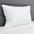Pictured: White pillow on a white comforter against a grey fabric headboard.