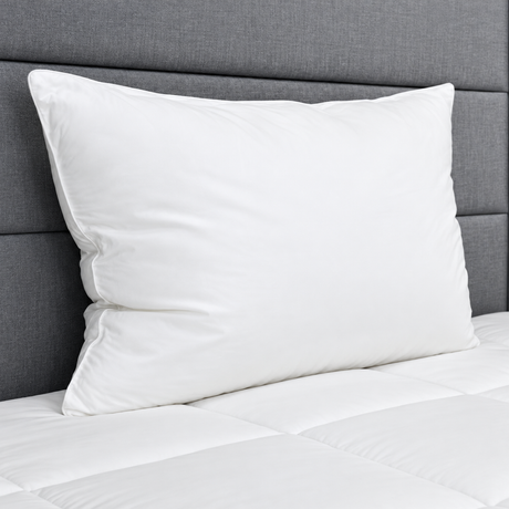 Pictured: White pillow on a white comforter against a grey fabric headboard.
