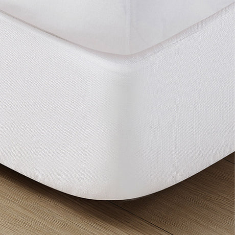 Pictured: White covered box spring on a wood floor.
