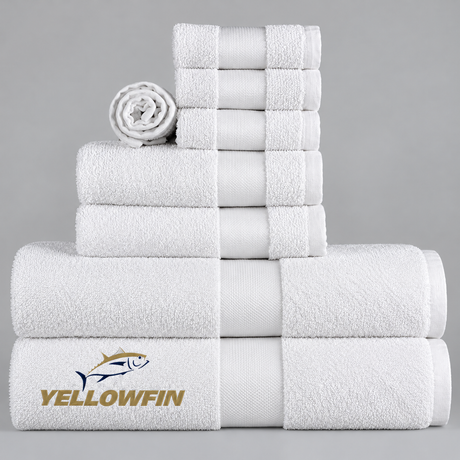 Pictured: White towels with a cam border in the center. The towels are neatly folded and stacked according to size. In the bottom left corner is the YELLOWFIN logo.